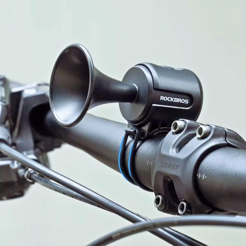 Close-up of black bike bell securely mounted on handlebar, delivering 120dB of sound for maximum visibility and safety.