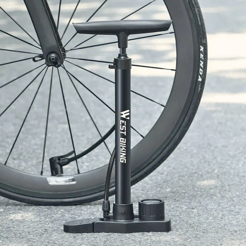 Bike floor pump next to road bike tire on asphalt, ready for inflation