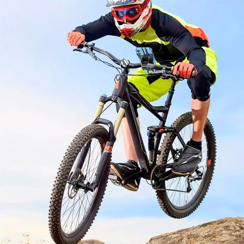 Cyclist in mid-air with phone securely mounted on handlebars, showing durability of bike phone holder in action.
