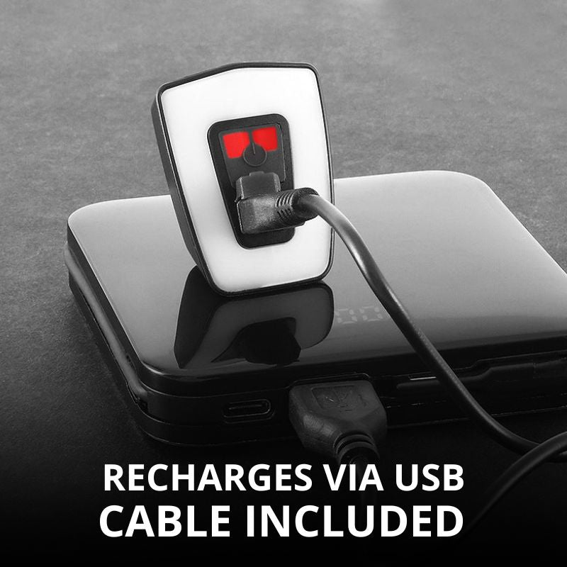 Bike light charging via USB on a flat surface.