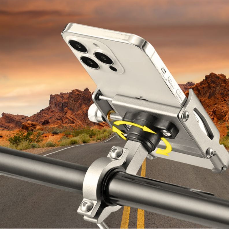 Close-up of the aluminum phone holder mounted on a bike handlebar, set against a desert road background. Highlights the rotation mechanism and solid build.