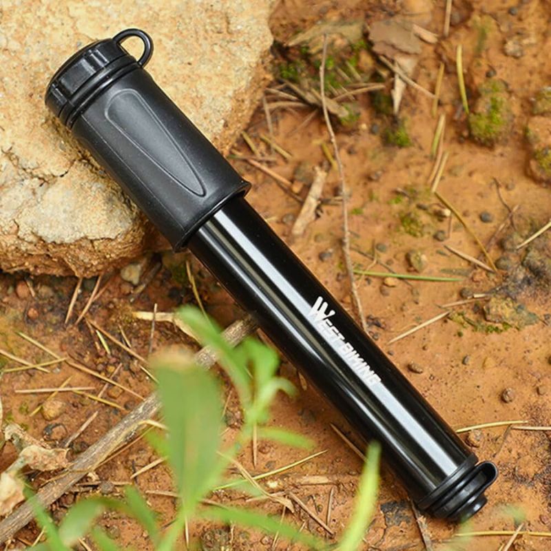 Compact pump resting on forest ground, ideal for outdoor cycling use